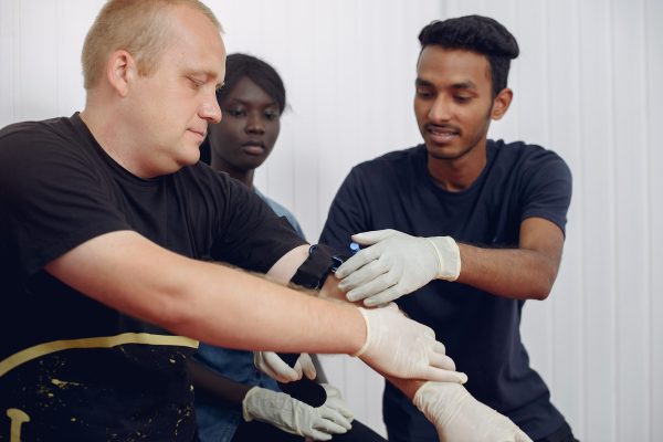 People are practicing medicine.Men and women are learning how to properly provide first aid.
